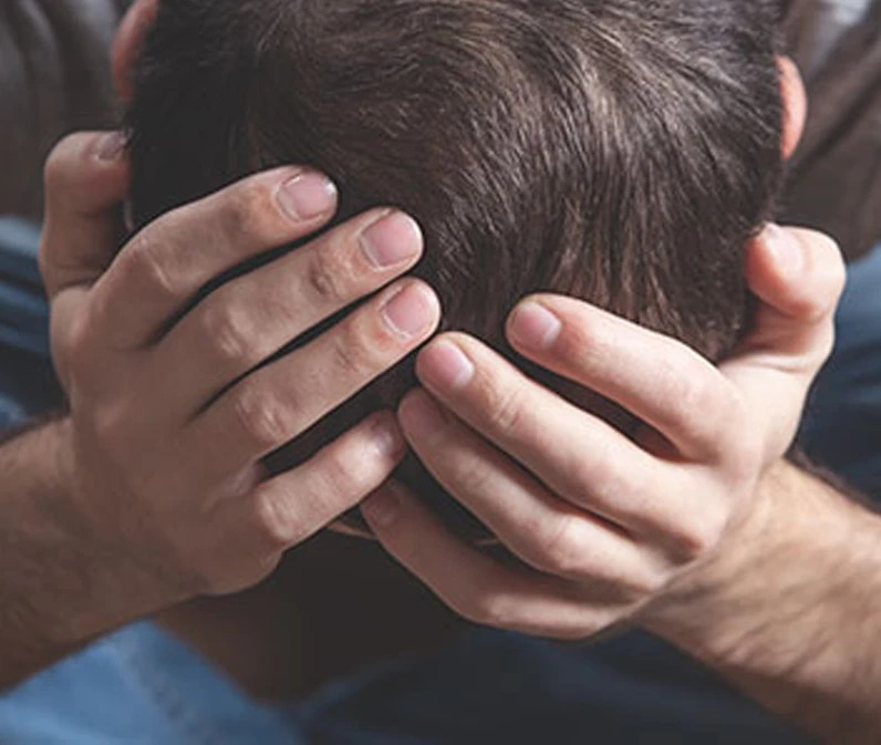 Man holding head in hands, expressing stress or frustration.
